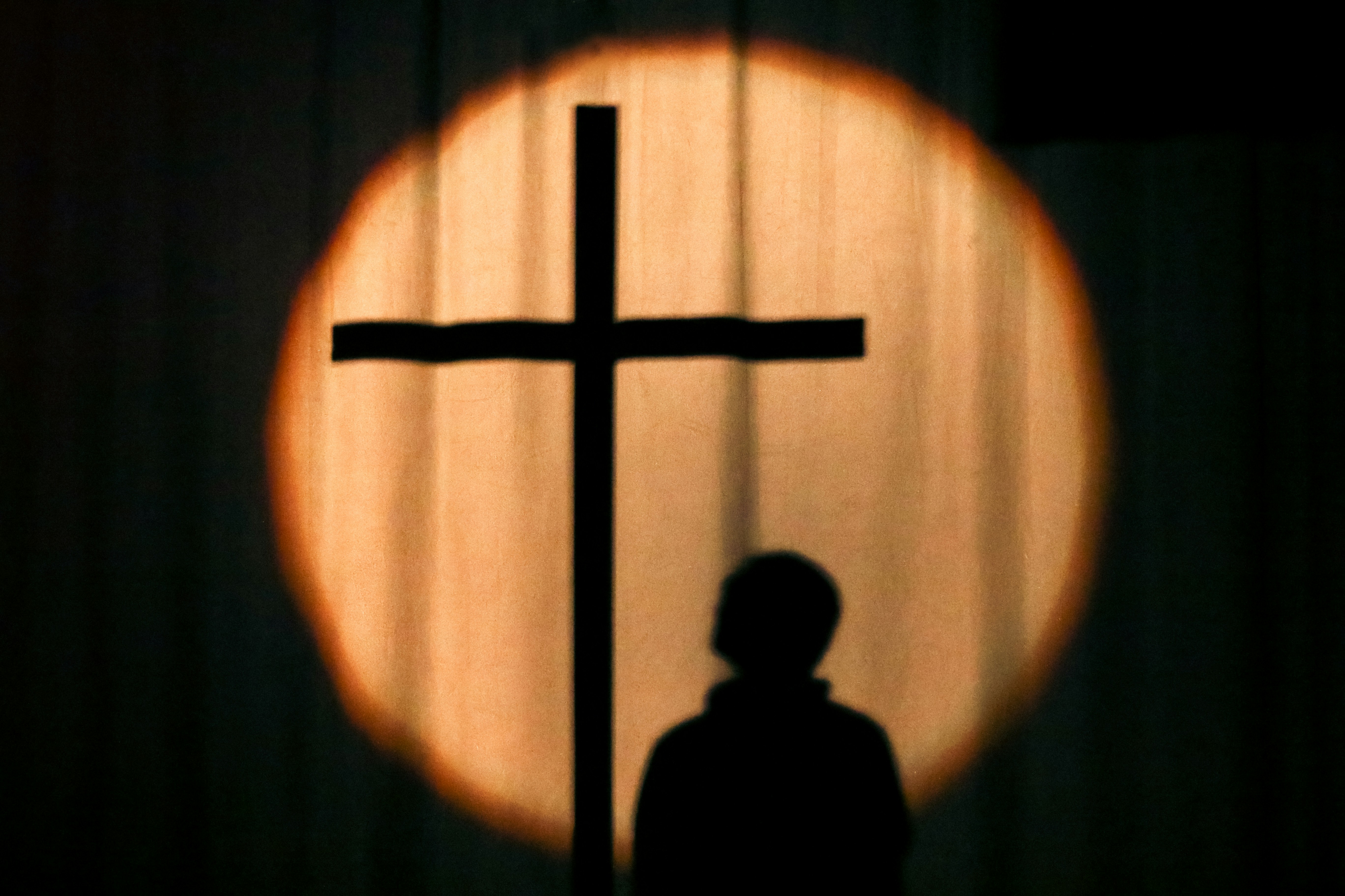 Person standing in front of a cross
