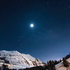 A big, bright star shins over snowy mountains