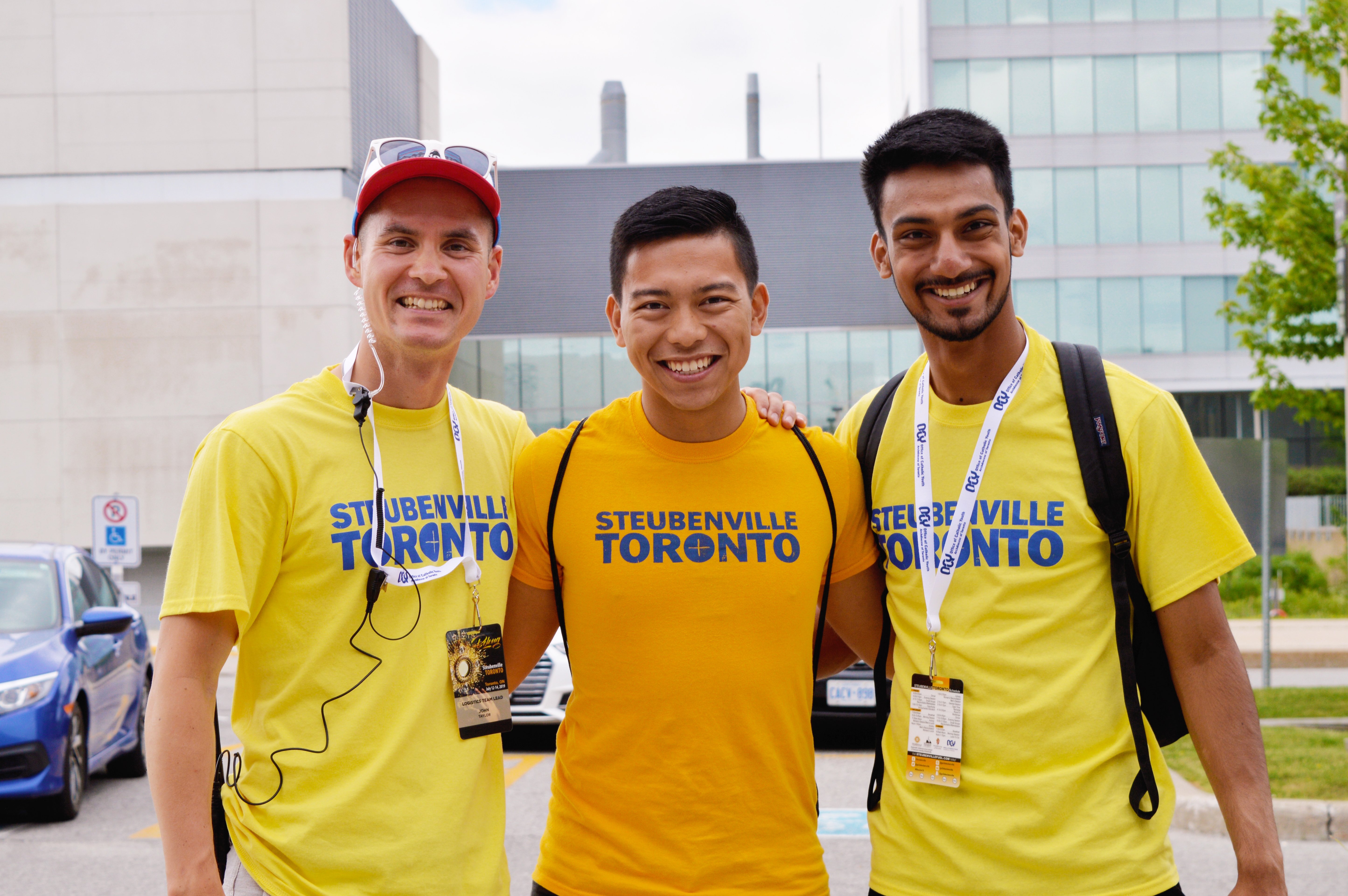 Three men of various ethnicities wearing yellow shirts and smiling together
