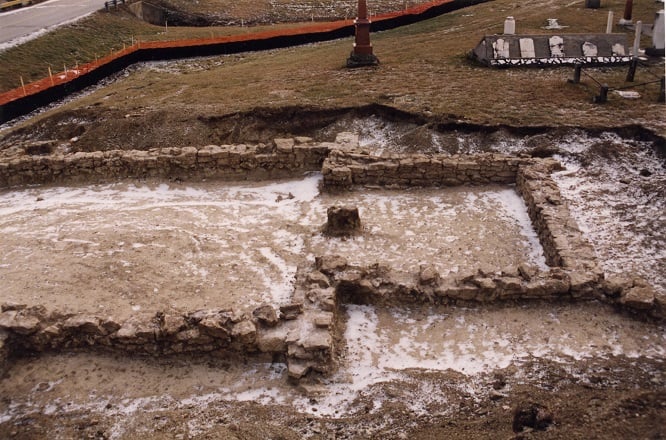 Archaeological site with an excavated stone church foundation with grave stones in the background