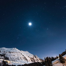 A big, bright star shins over snowy mountains