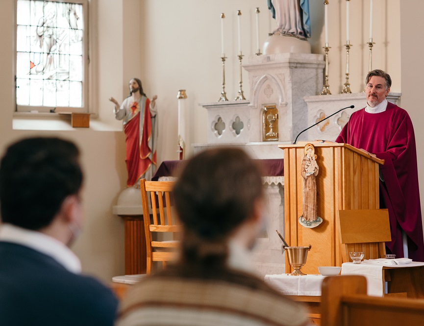 A priest speaks to the faithful from an ambo in a church