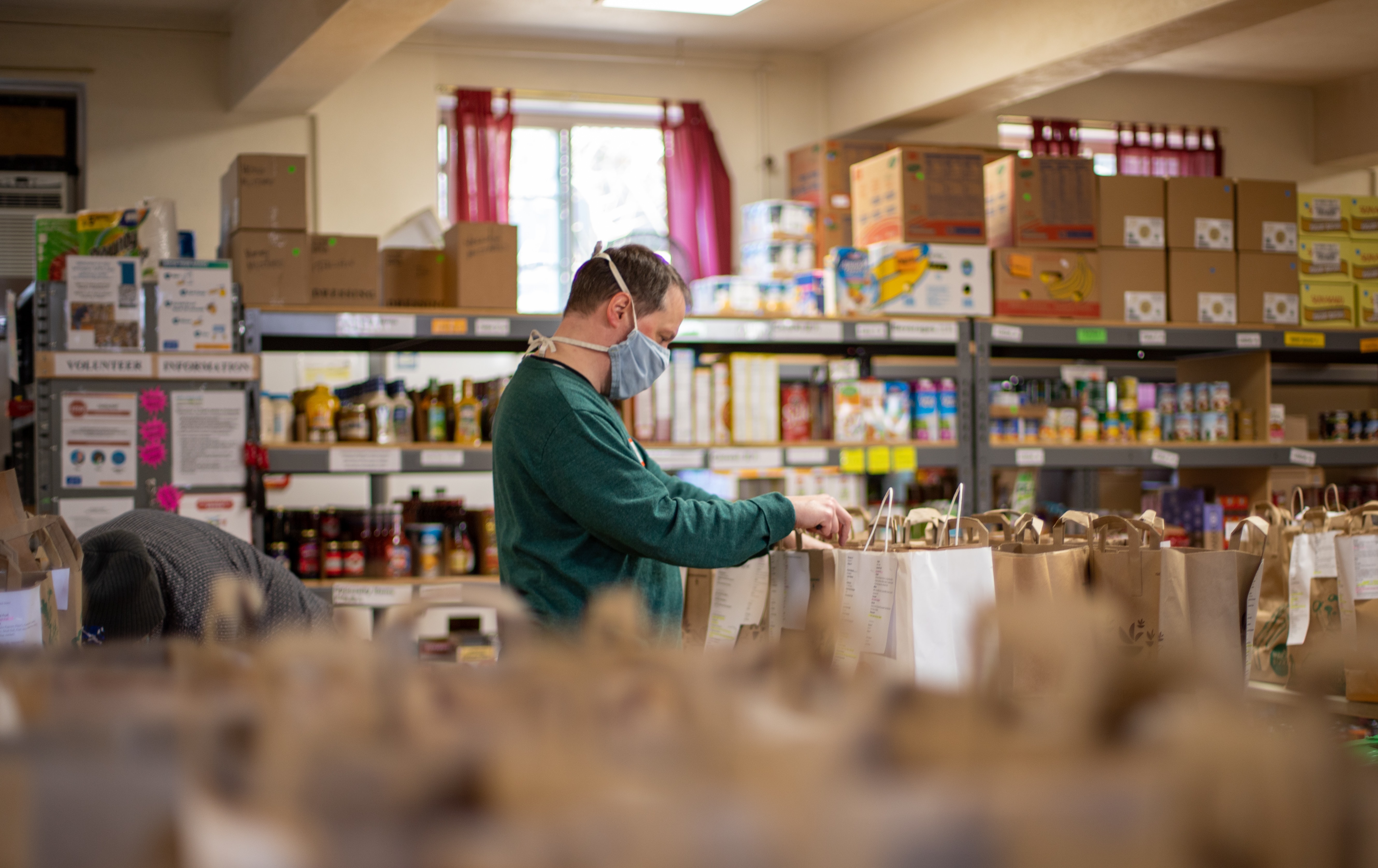 A person wearing a mask fills bags in a food bank