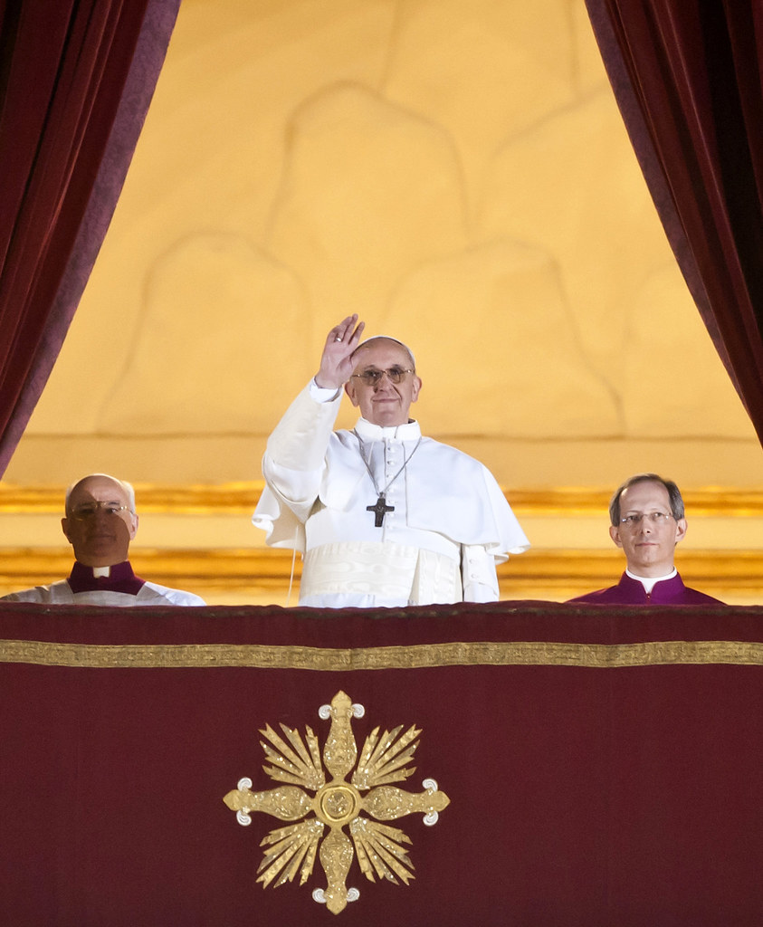 Pope Francis smiles and wave from a Vatican balcony after being selected Pope