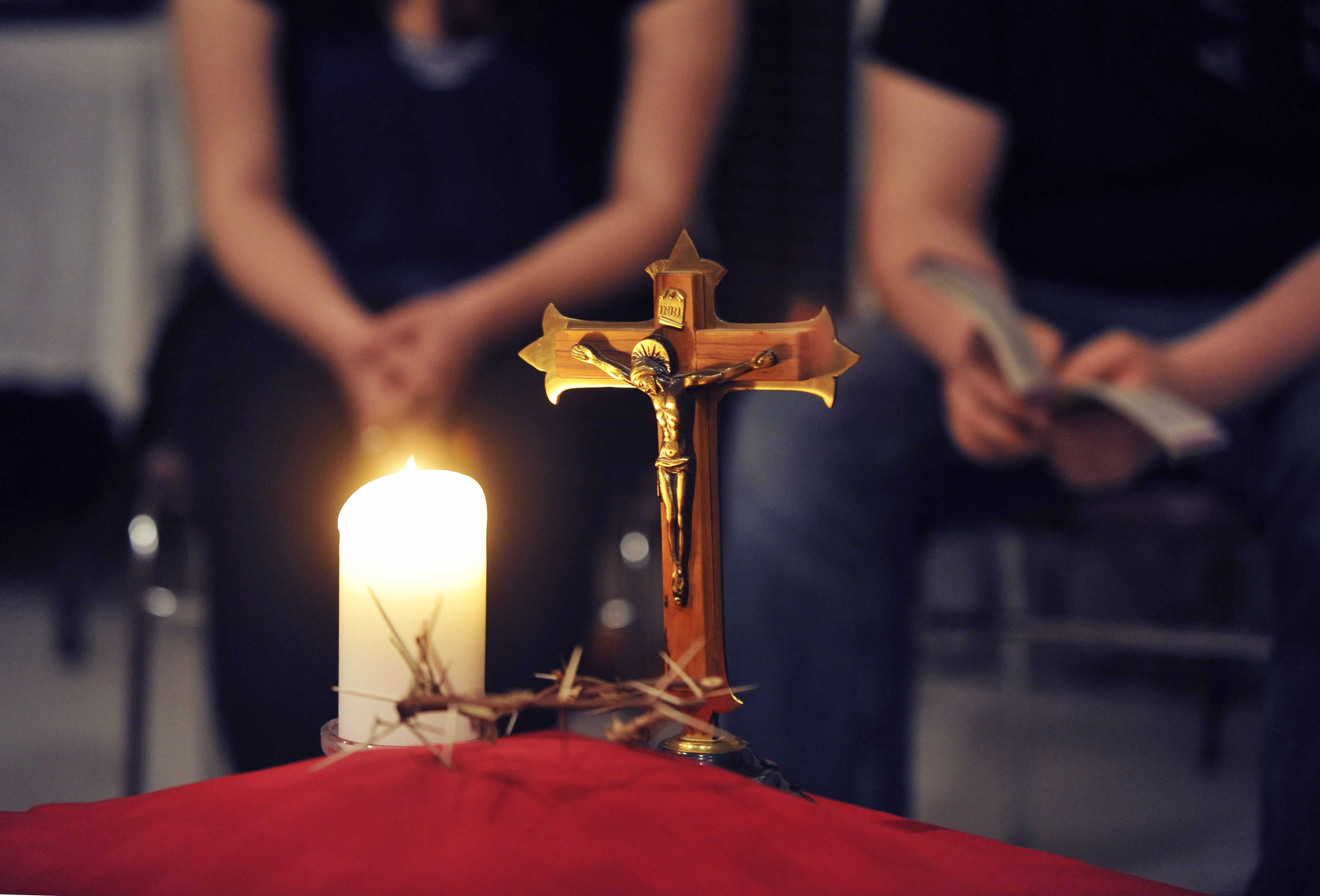 Praying hands by candle and cross