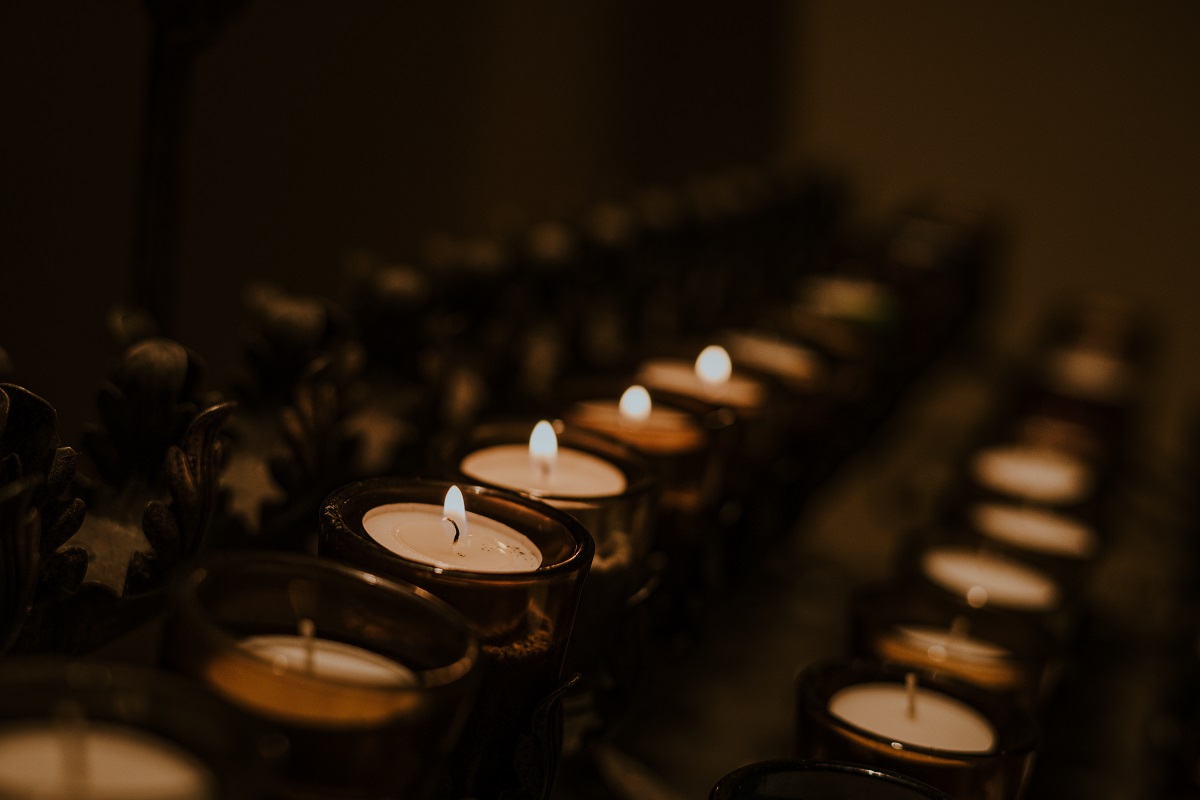 A side angle on lit votive candles in a church