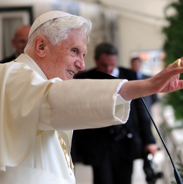 Pope Benedict XVI waves to a crowd from a bent over position