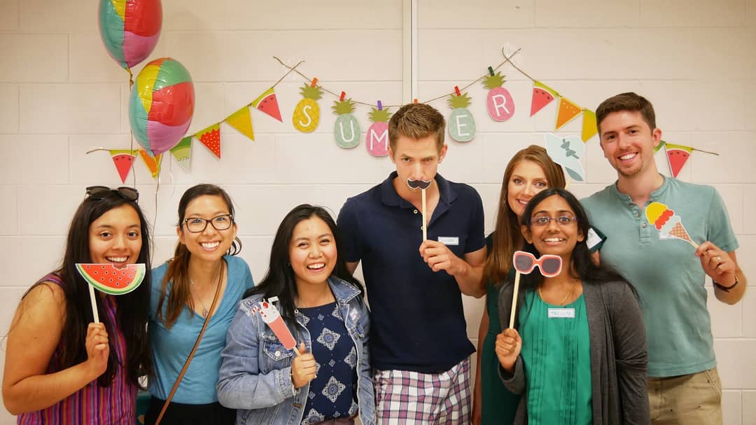 Group of male and female young adults using summer-themed props and costumes to take a party photo