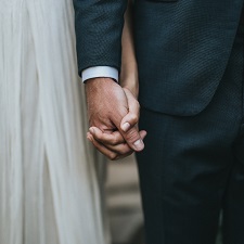 Focused on the hands of a bride and groom on their wedding day. They're holding hands