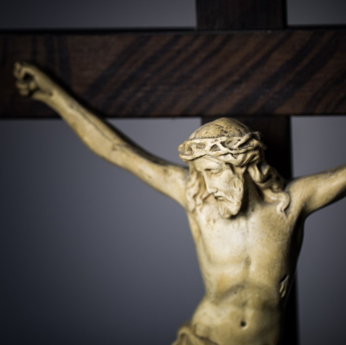 A close -up of Jesus on a crucifix with a grey background