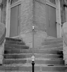 A complicated staircase up to a church, crucifixes on the handrail, photo in black and white