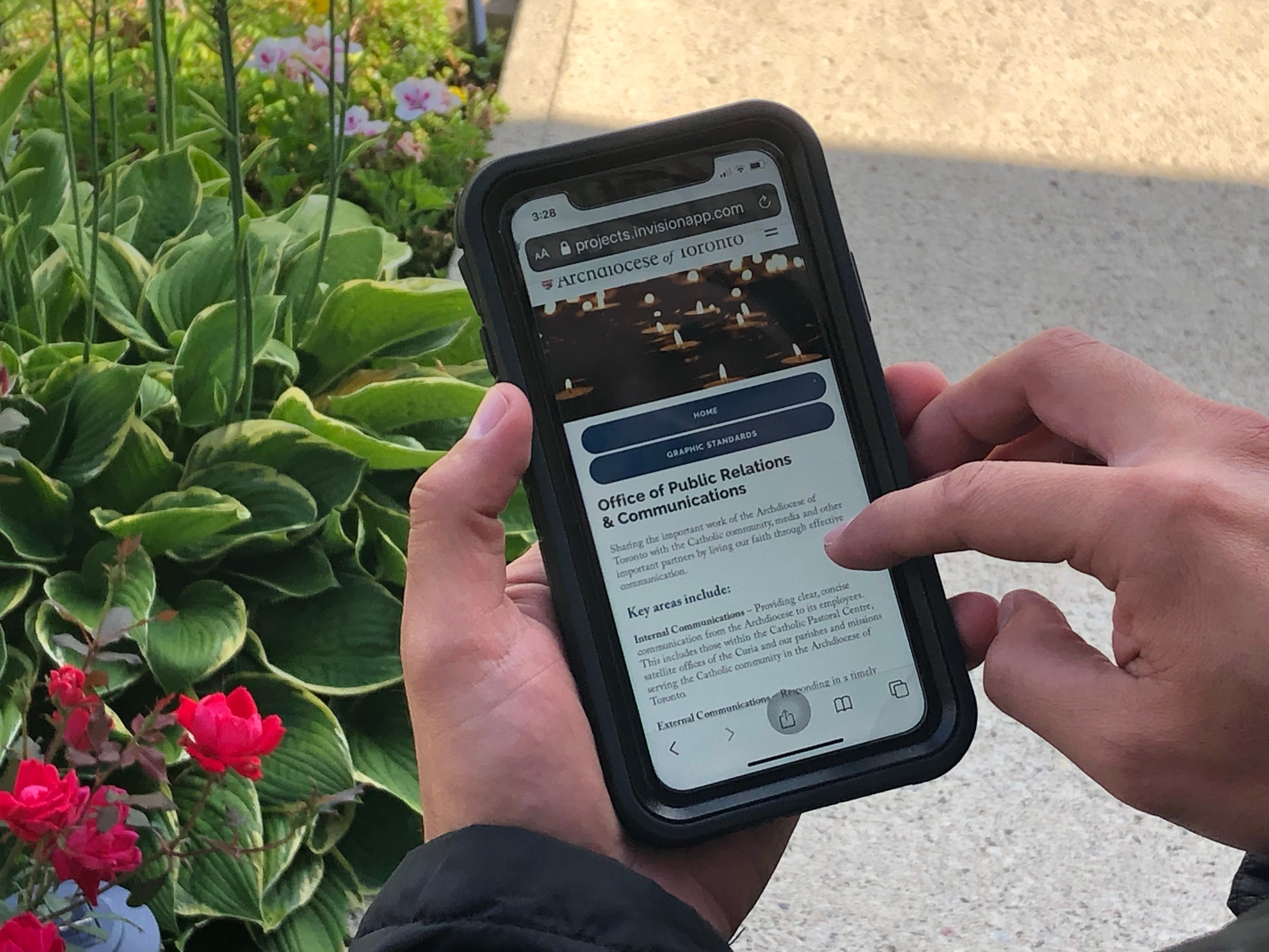 A person on their phone looking at the new Archdiocese of Toronto website
