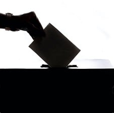 A silhouette of a woman's hand casting a ballot