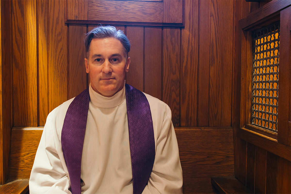 A priest sits in a confessional