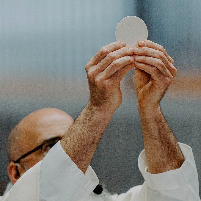 A priest holds up the Eucharist in a church