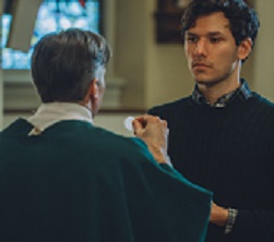 A man receives the Eucharist from a priest