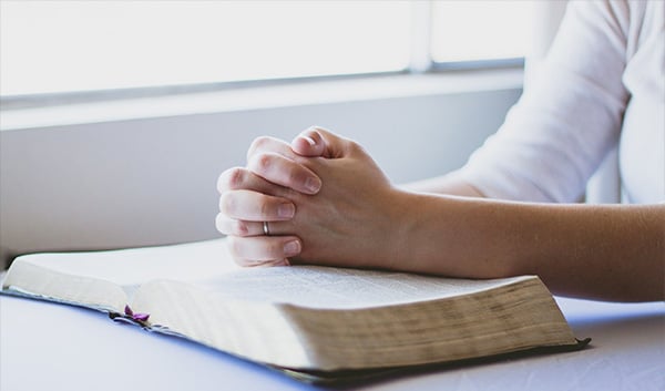 Praying hands with open book