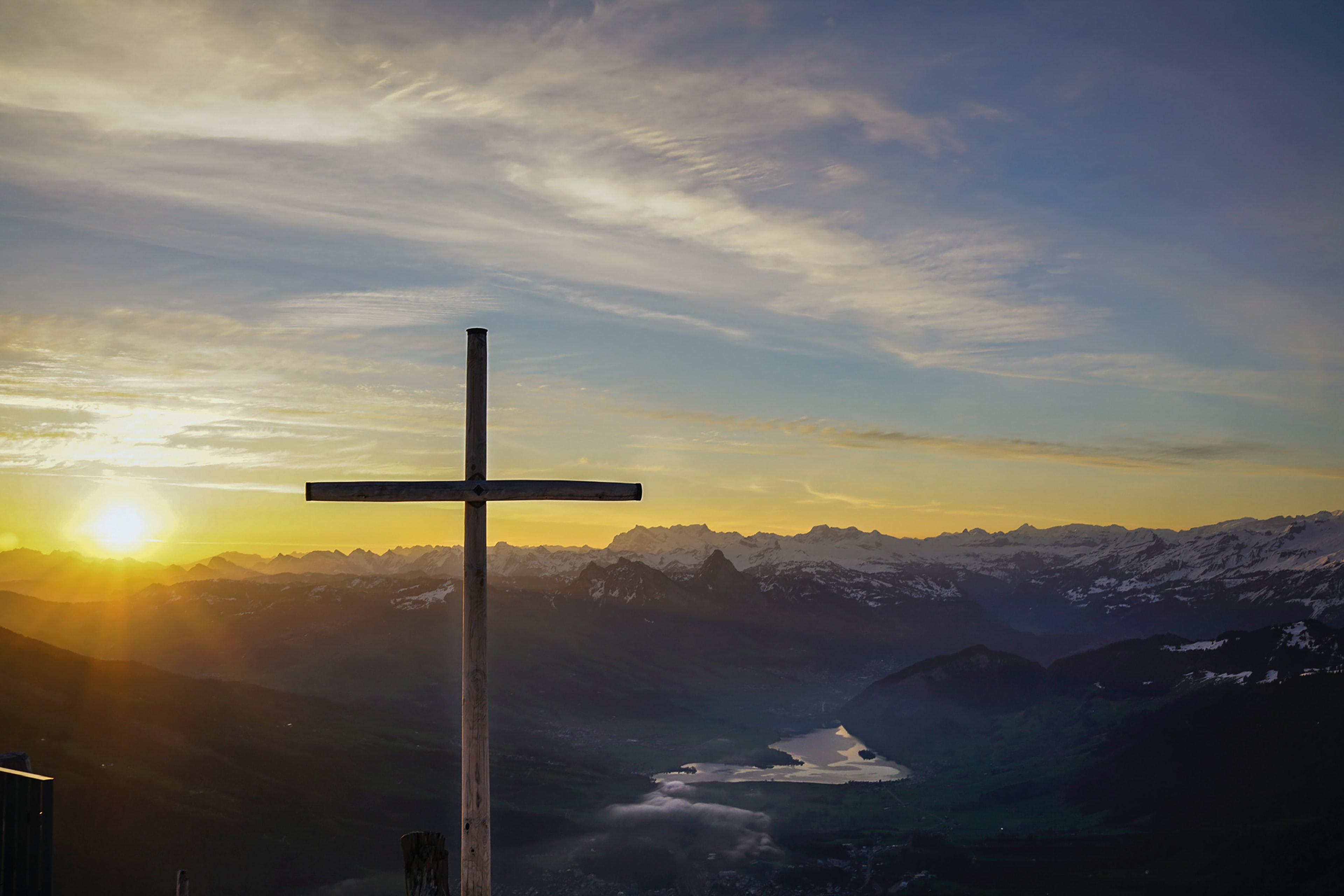 Cross in the mountains with sunlight behind it