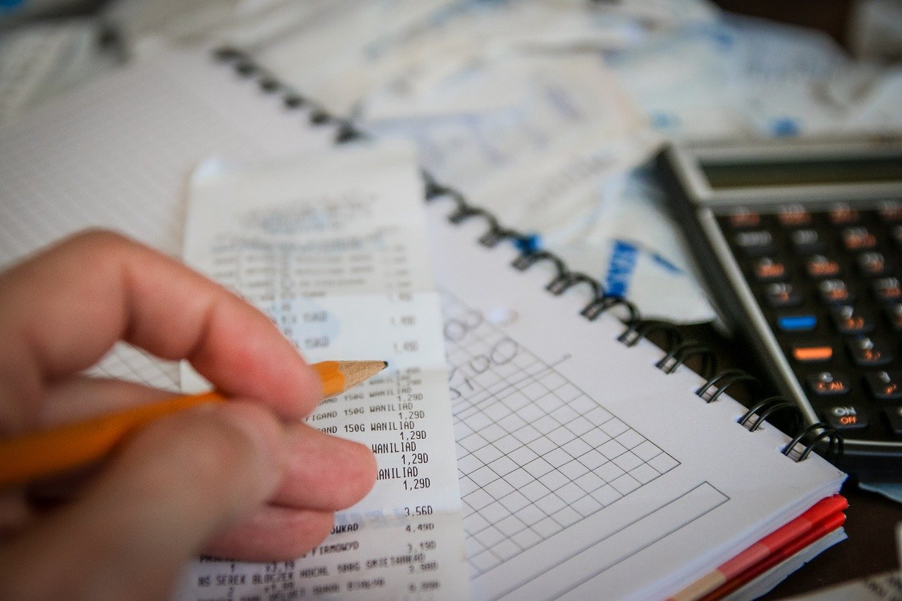 A man does financial work with a calculator, a notepad and a receipt