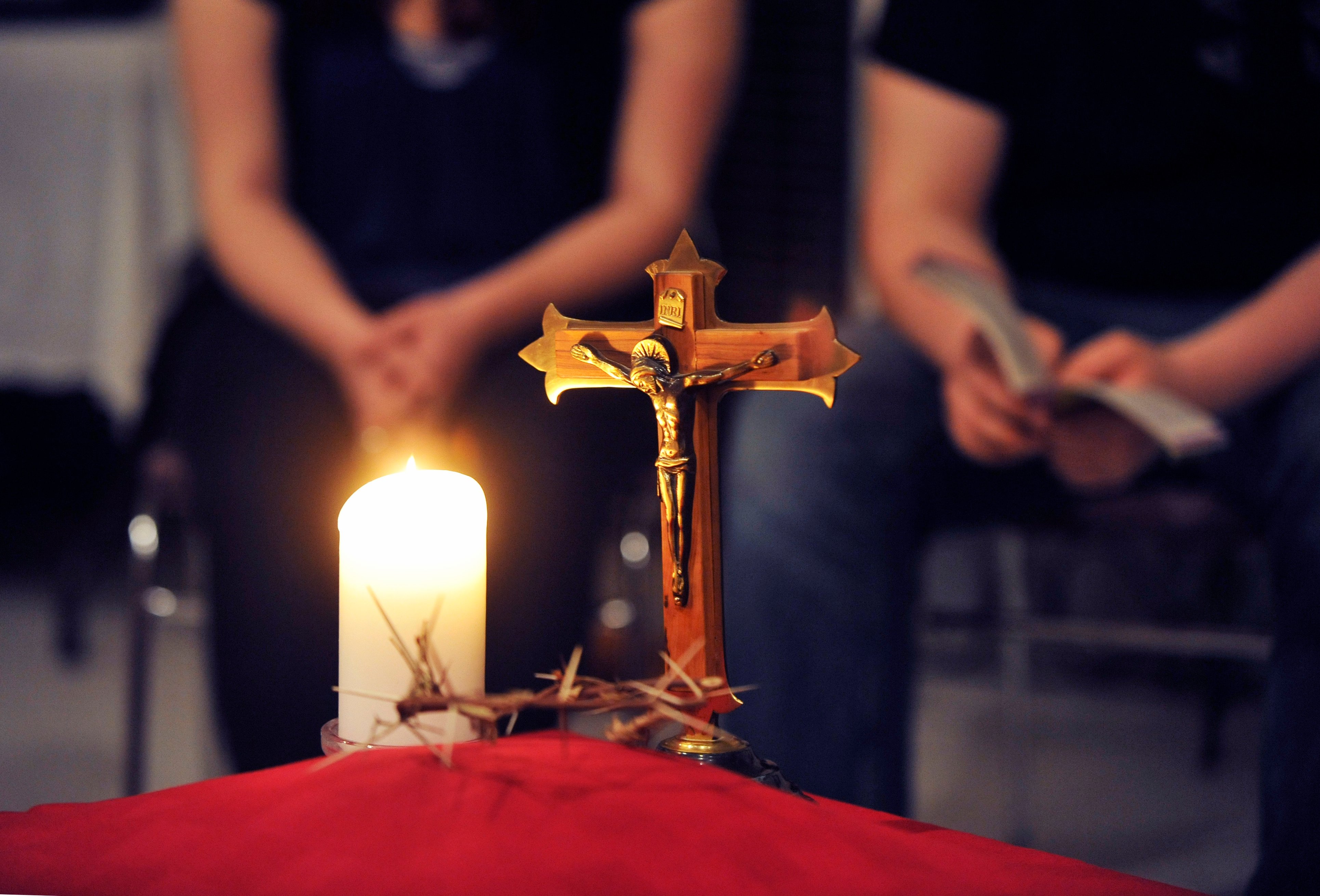 Praying hands by candle and cross