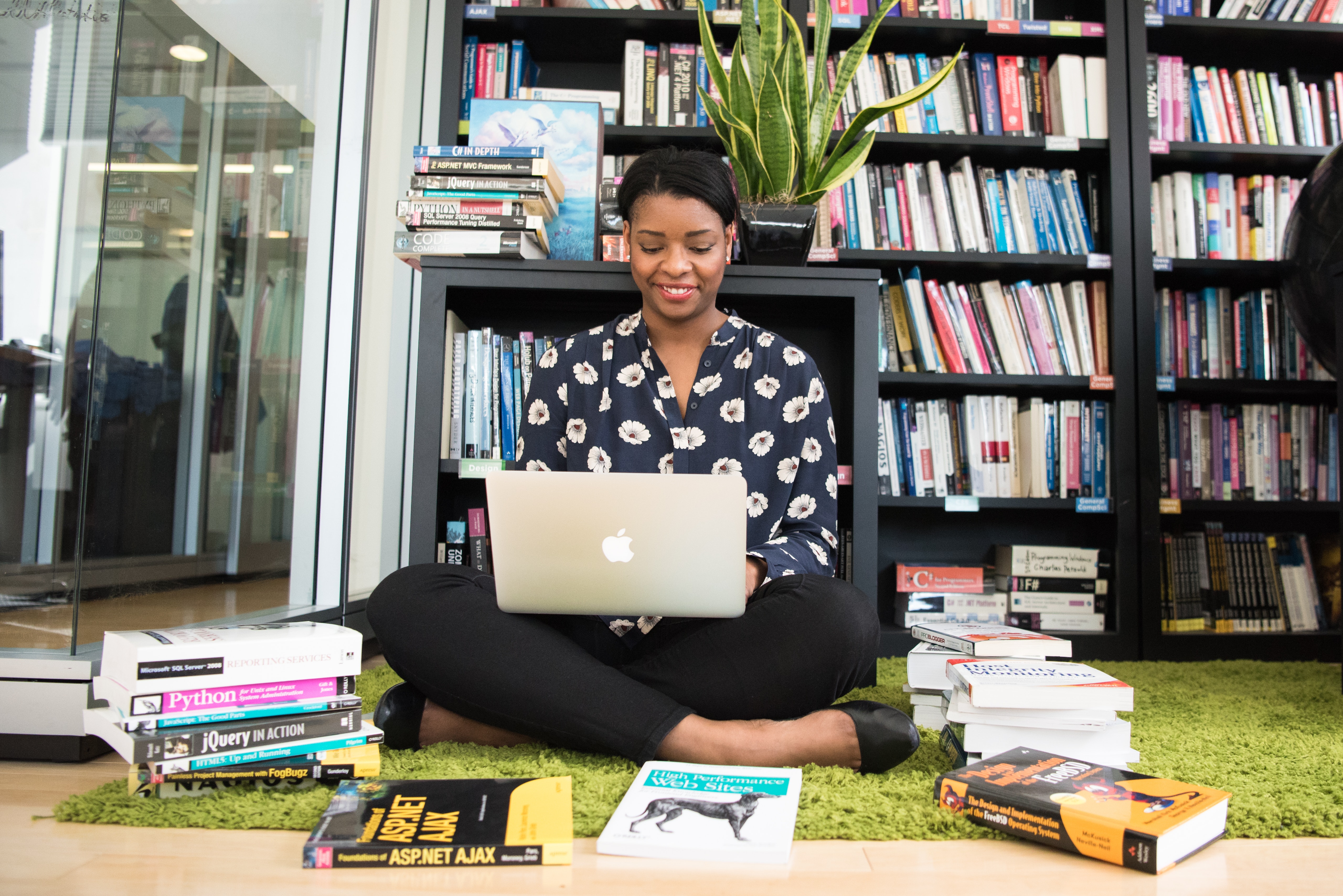 woman sitting on floor with laptop on lap surrounded by books, Adobe file 1181571.jpg