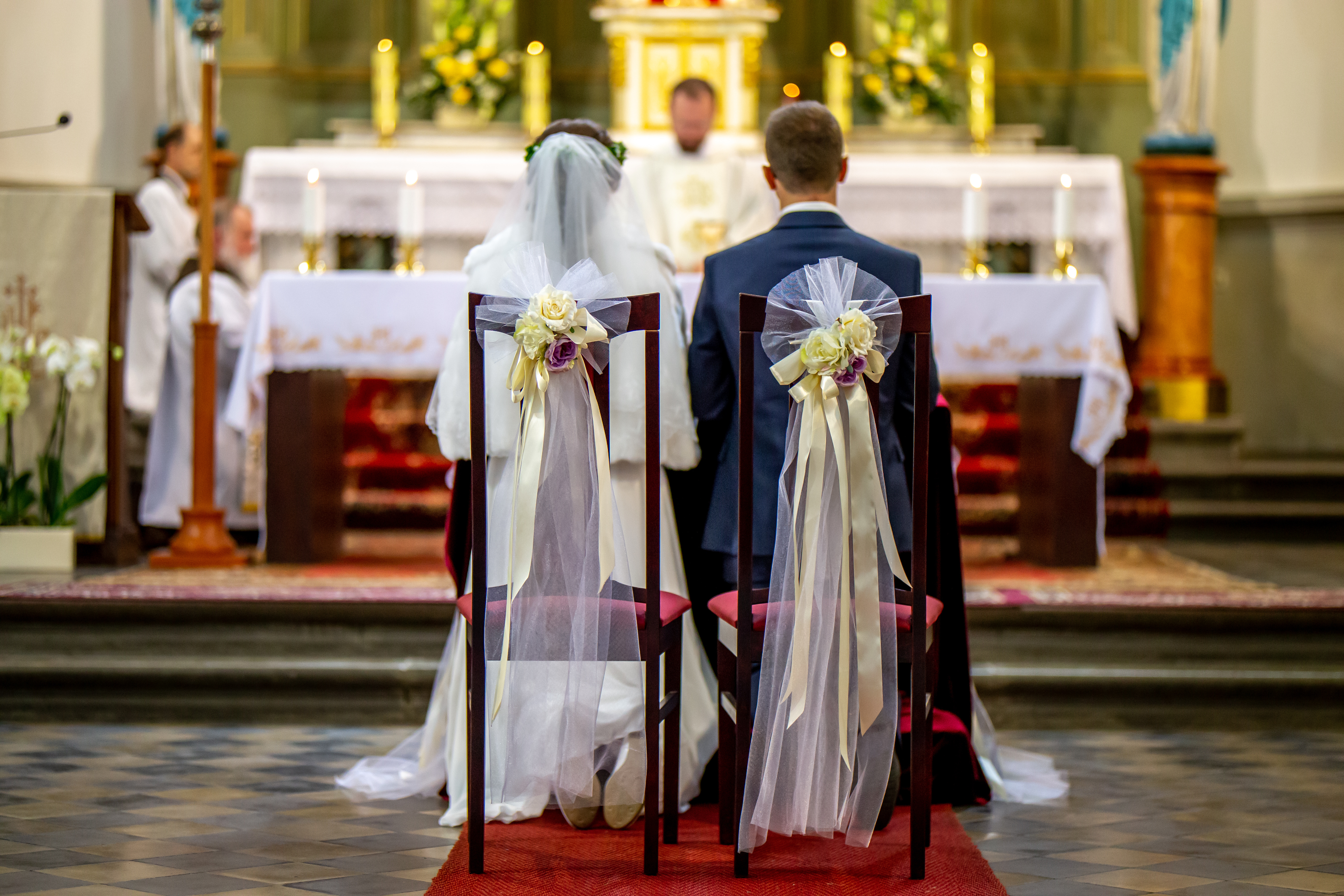 wedding ceremony, couple sitting on chairs in front of sanctuary, view from the back