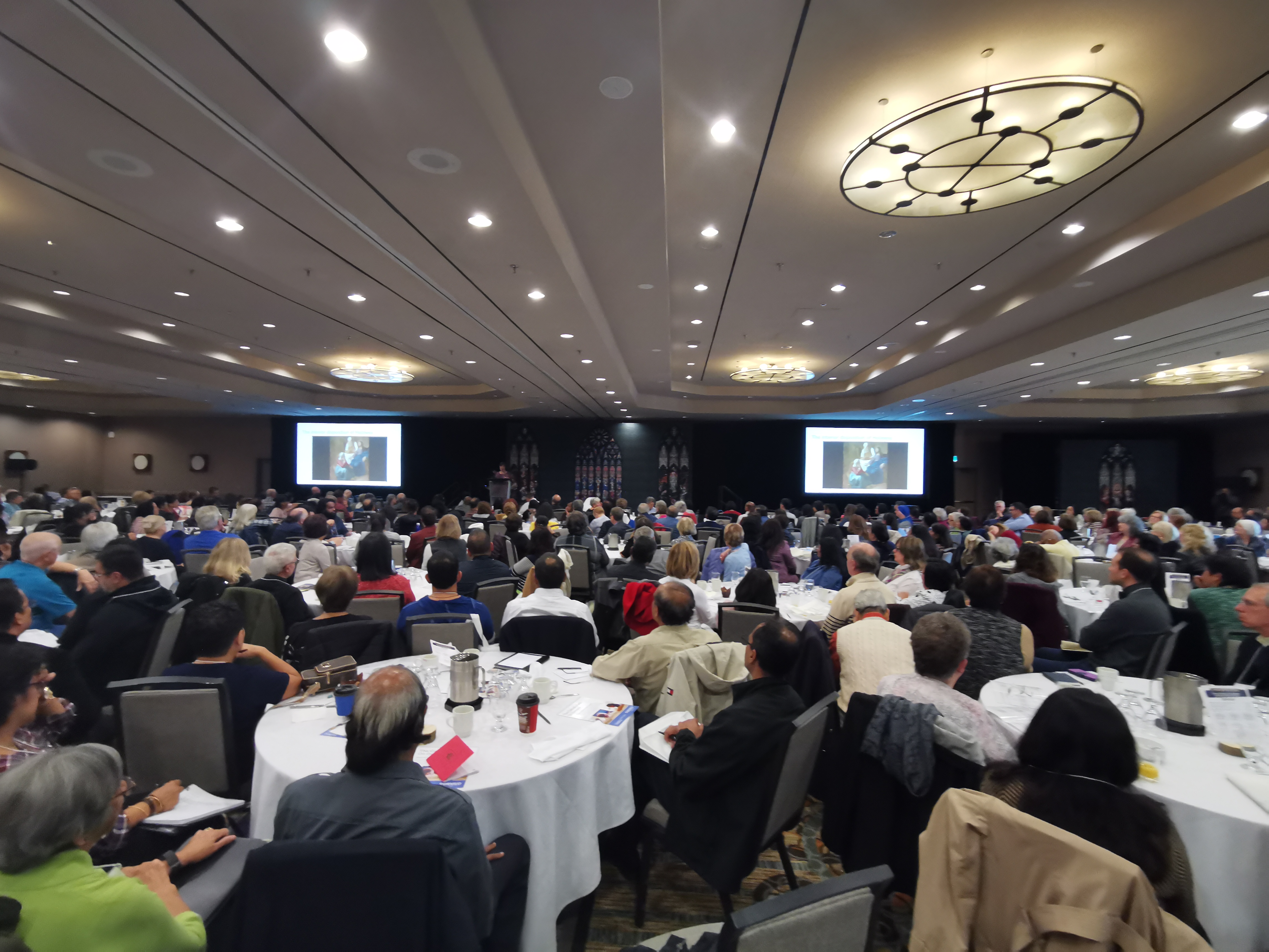 image of attendees sitting in main hall listening to speaker at conference