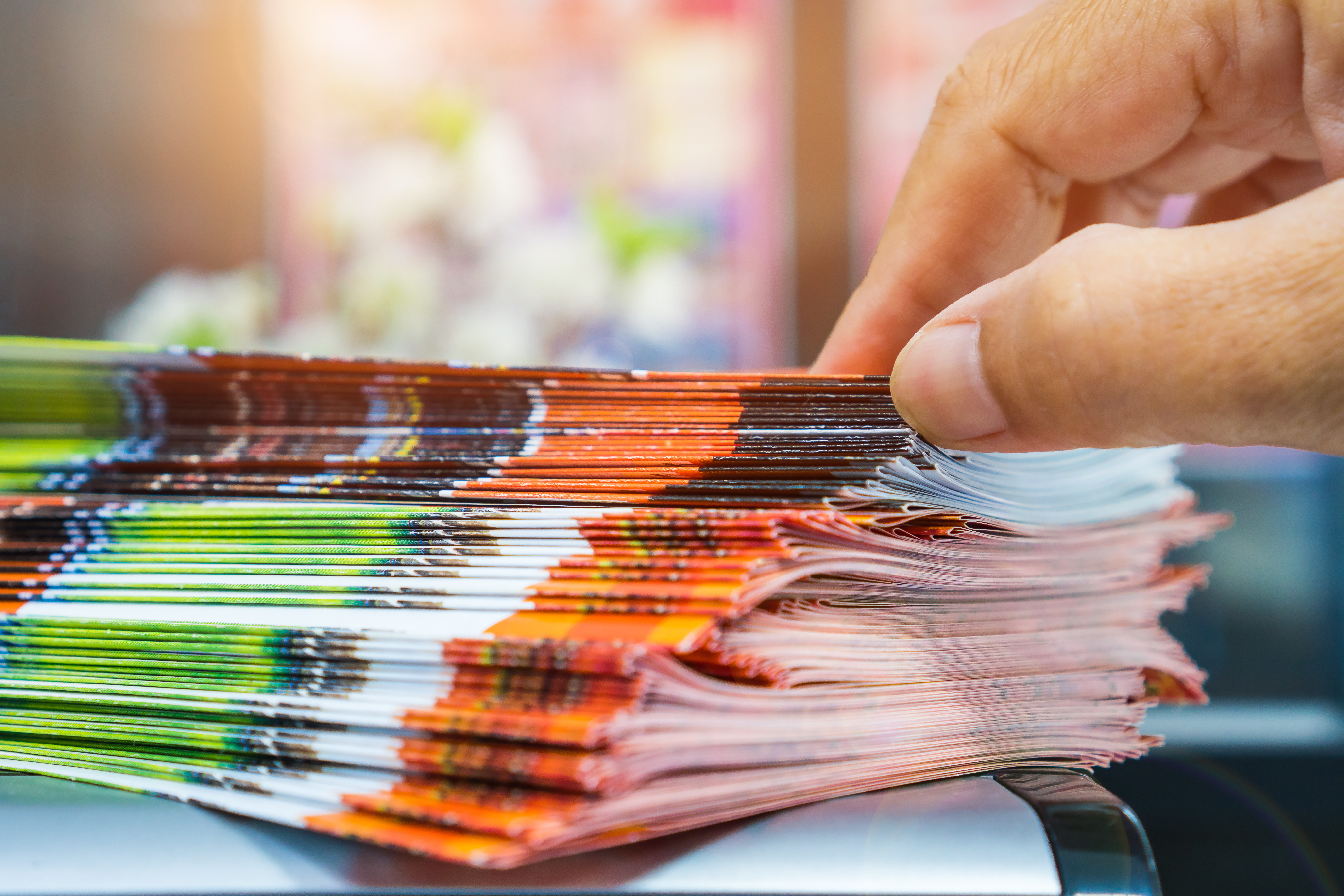 image of stack of newsletters and  a hand grabbing one (AdobeStock_217137034)