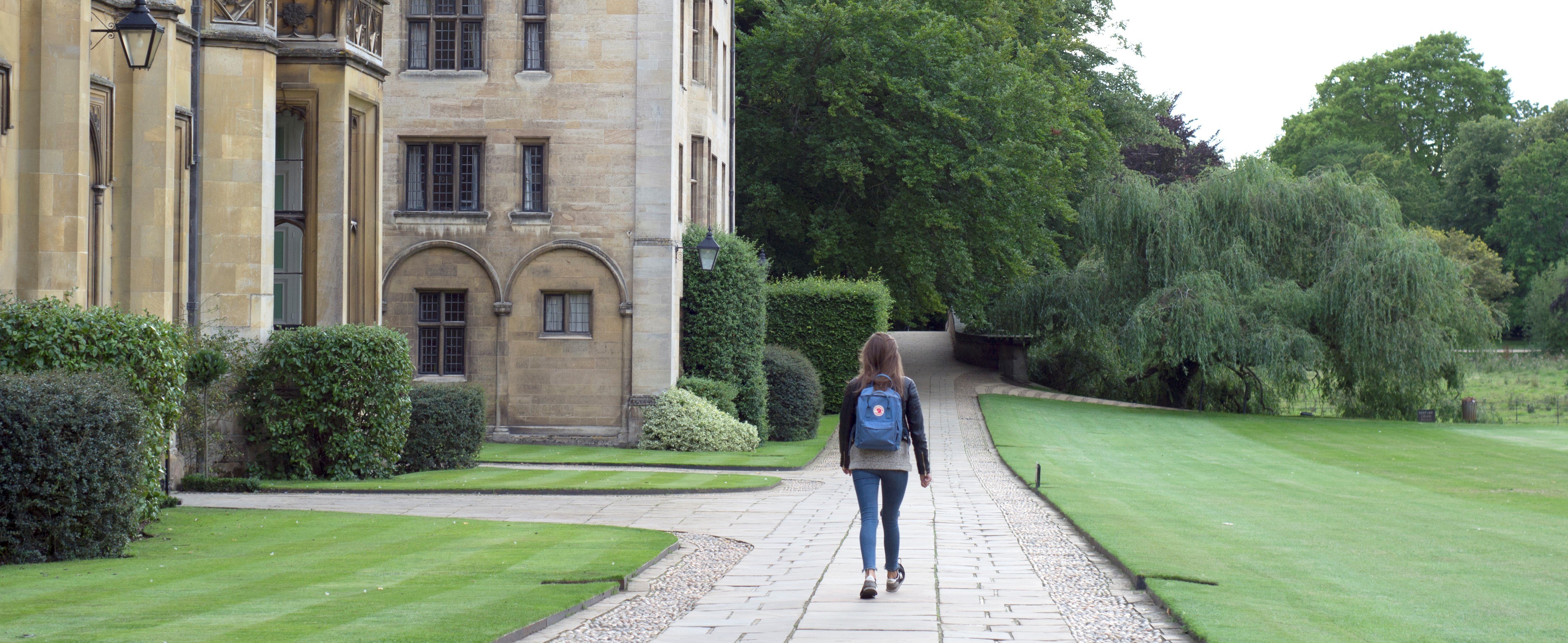 Female student with blue backpack walking around university campus