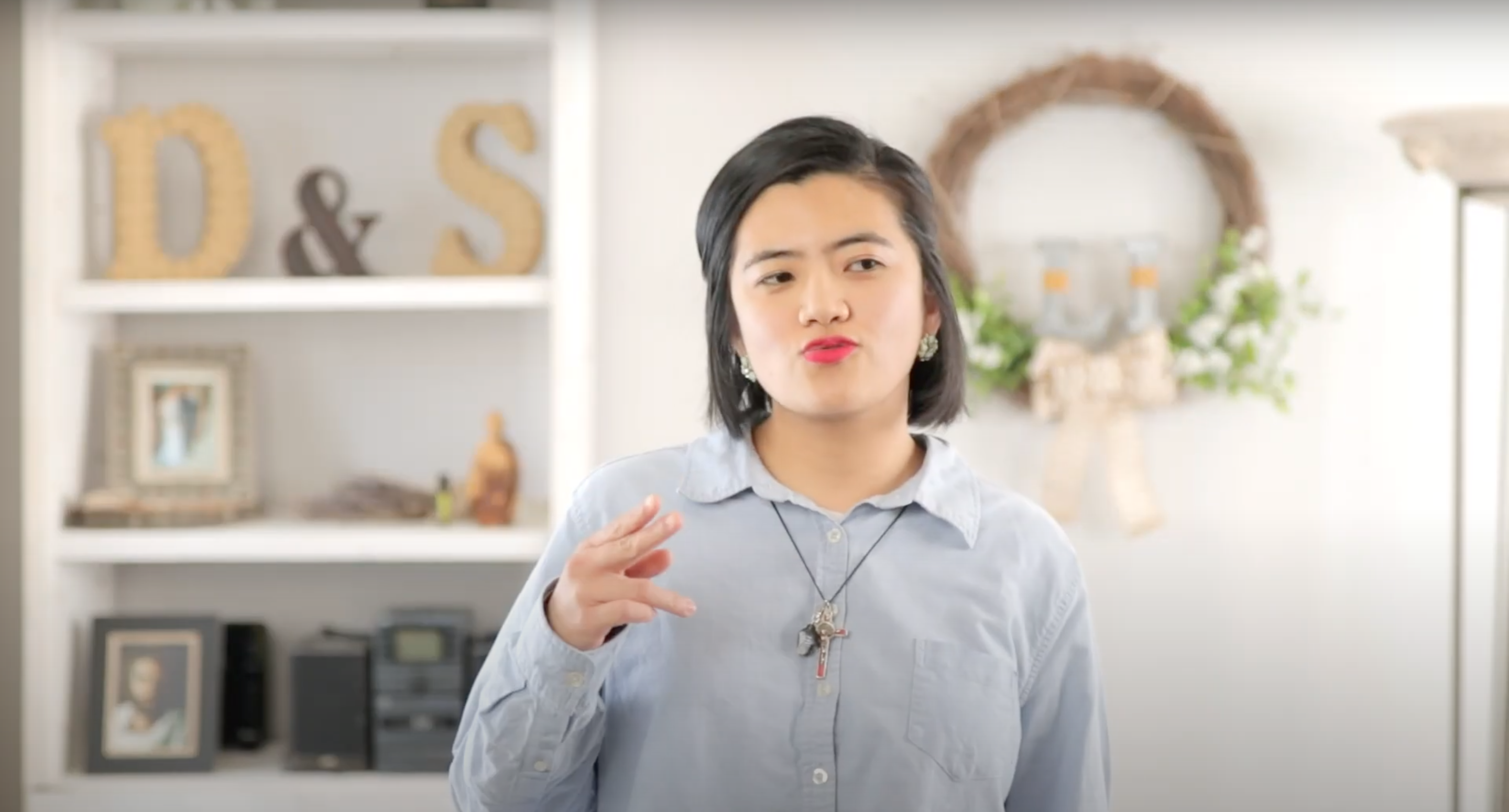 Young woman in a blue button-up shirt making a peace sign while pouting her lips in a funny way