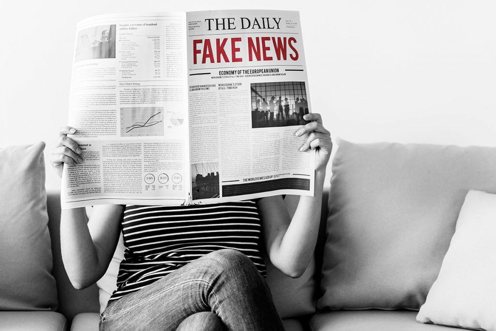 A woman reads a paper with the headline "Fake News"