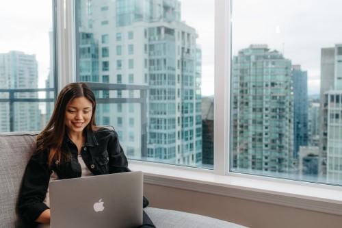 young woman working on her laptop in her home in her condo that overlooks downtown