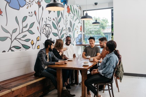 group of young adults sitting around a table, drinking coffee, and discussing our Catholic faith