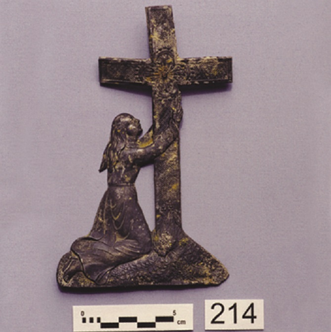 Metal coffin decoration with Mary kneeling before the cross