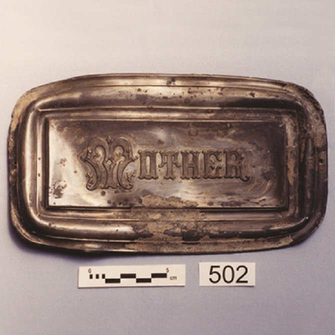 Metal coffin name plate reading "Mother"