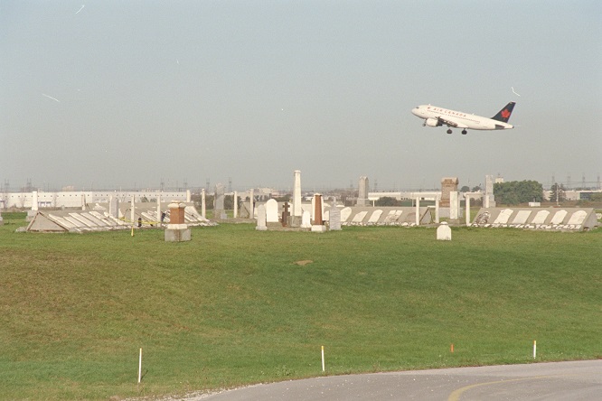 Wide shot of historic Elmbank cemetery with a plane taking off in the background