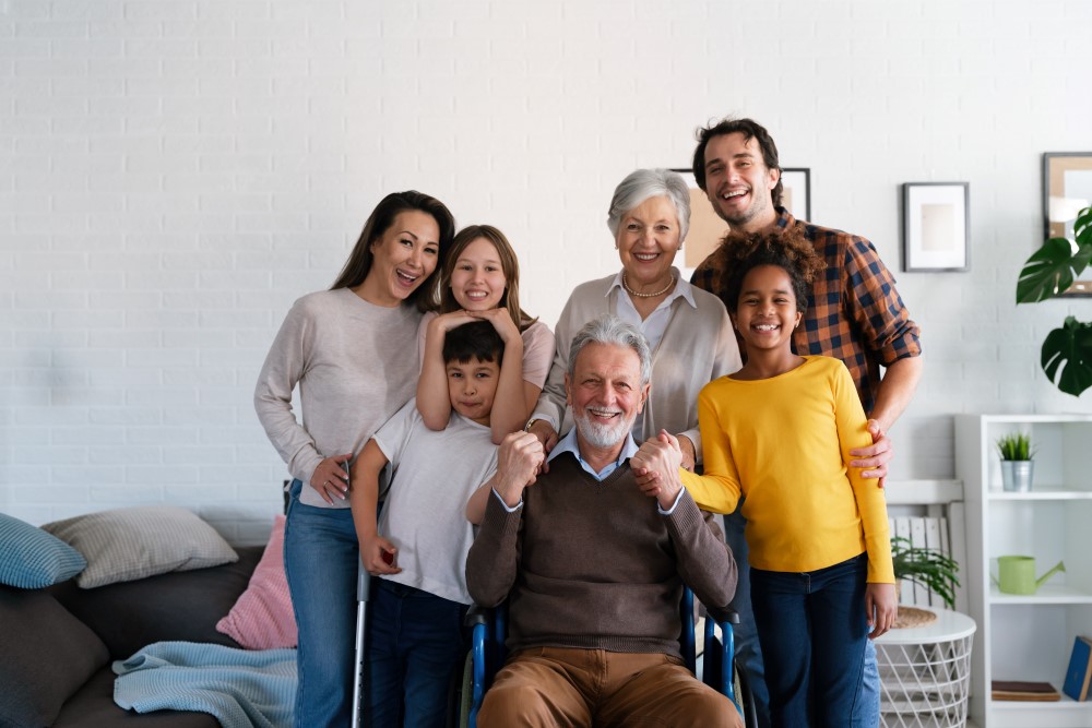 Joyful, blended family surrounding older man with a wheelchair