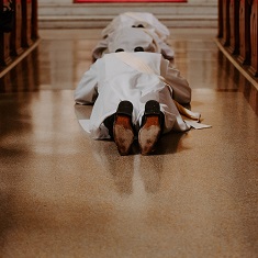 Two men lay prostrate on the floor at a priestly ordination